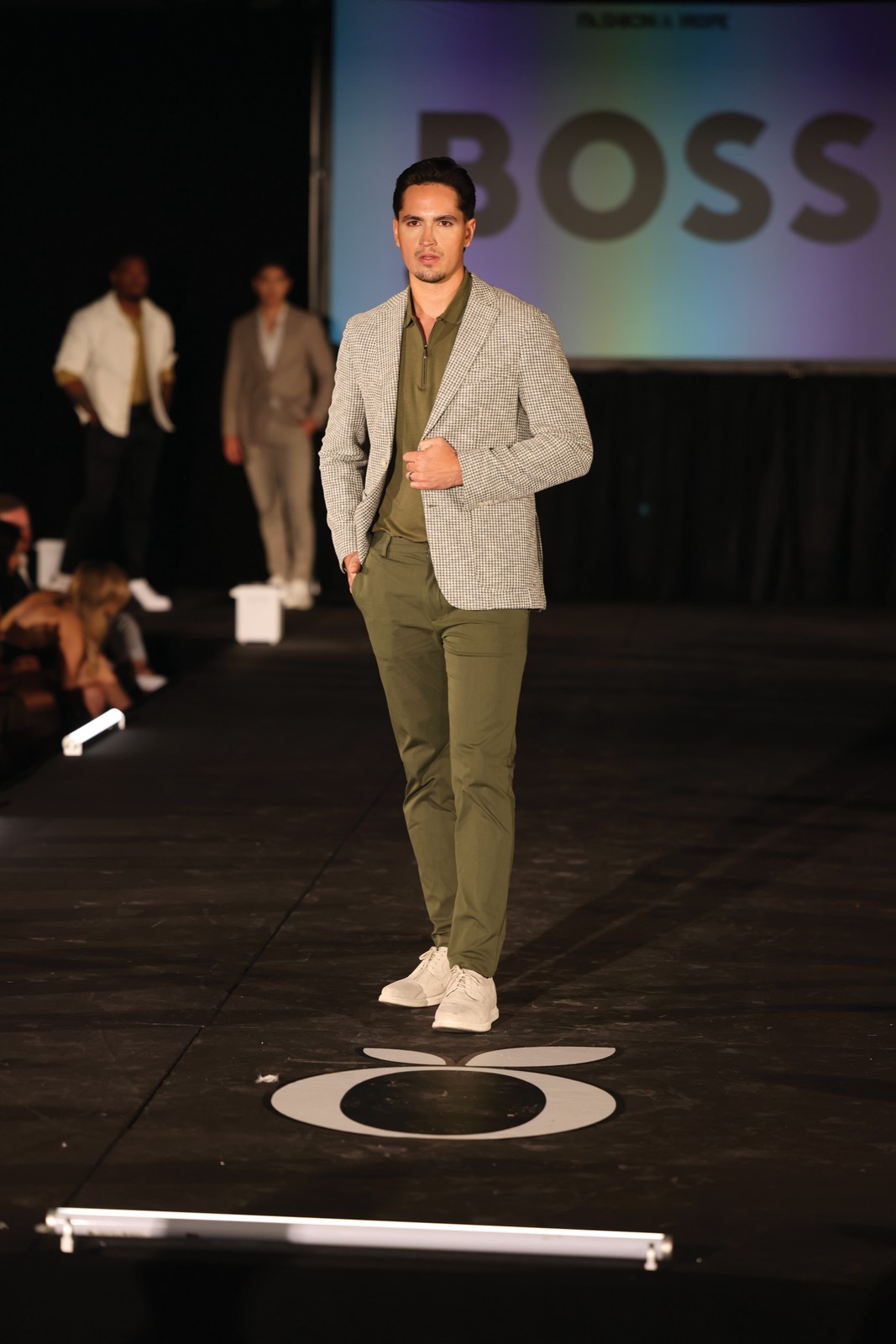 Fashion & Hope 2026 Menswear Look A male model in a tailored sage suit walks the Fashion & Hope 2026 runway