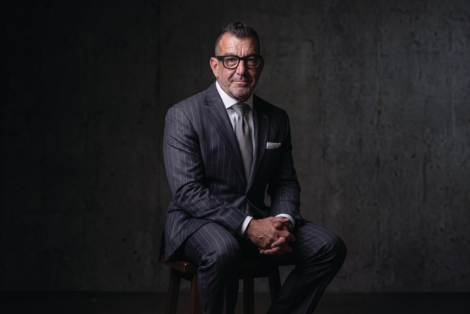 Jeffrey “Jack” Gordon Attorney Jeffrey “Jack” Gordon seated in a pinstripe suit against a dark wall