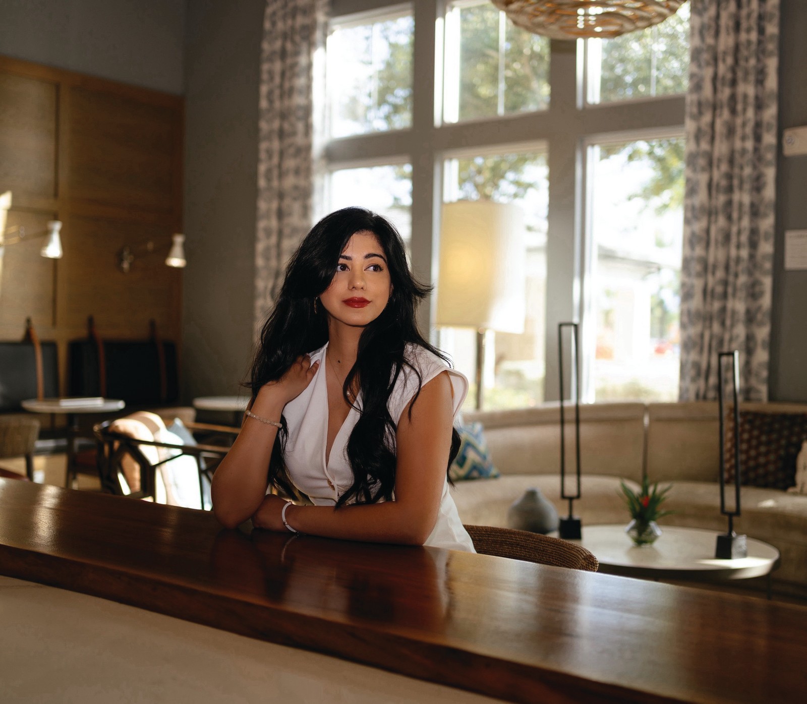 Reflection – Maha Chaudhry 2 Maha Chaudhry seated at a polished wood table in a sunlit room